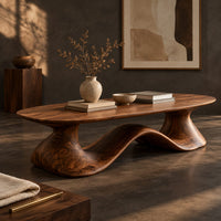 Corner detail of long oval coffee table on a flowing wave shaped wooden pedestal base beside wood, brass and linen samples
