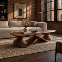 Long oval coffee table on a flowing wave shaped wooden pedestal base in an industrial loft living room with exposed brick