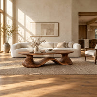 Long oval coffee table on a flowing wave shaped wooden pedestal base in a bright open plan living room