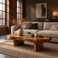 Long oval coffee table with a raw edged slab top on two block legs in an industrial loft living room with exposed brick