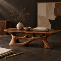 Corner detail of long oval coffee table with a sweeping cutout base beside wood, brass and linen samples