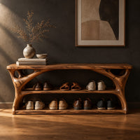 Long low shoe bench with open shelves and branching sculpted sides in a dark studio against a charcoal plaster wall