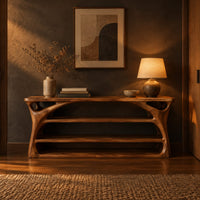 Long low shoe bench with open shelves and branching sculpted sides in a dark entryway at golden hour