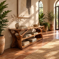 Long low shoe bench with open shelves and branching sculpted sides in a bright entryway with arched windows and plants