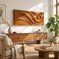 Long horizontal wall panel carved with sweeping waves and a raised disc in a bright sunroom with green plants