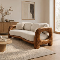 Sofa with a sculpted wood frame, open loop arms and a long seat cushion in a Scandinavian living room with white walls