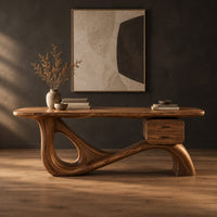 Desk with an oval top, a looped sculpted base and a two drawer box in a dark studio against a charcoal plaster wall