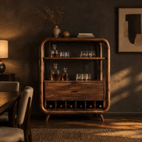 Bar cabinet with a looped wood frame, open shelf and slotted base in a dark dining room at golden hour