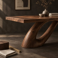 Corner detail of dining table with a sweeping ribbon base that folds into an open loop beside wood, brass and linen samples