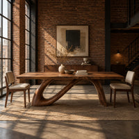 Dining table with a sweeping ribbon base that folds into an open loop in an industrial loft dining room with exposed brick