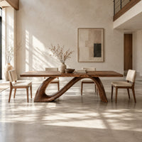 Dining table with a sweeping ribbon base that folds into an open loop in a bright open plan dining room