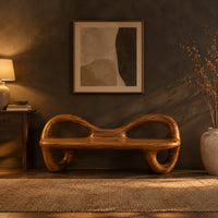 Bench with a flat plank seat, looped arms and ring shaped legs in a dark entryway at golden hour