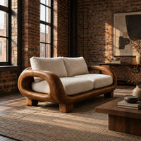 Sofa with thick looped wood arms, chunky block legs and cream cushions in an industrial loft living room with exposed brick