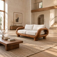 Sofa with thick looped wood arms, chunky block legs and cream cushions in a bright open plan living room
