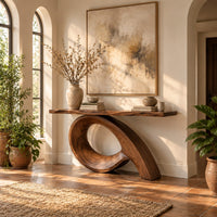 Narrow console table with a live edge top on a sweeping looped base in a bright entryway with arched windows and plants