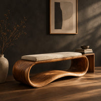 Wooden bench made from a looped ribbon frame with a slim cream cushion, three-quarter view showing the grain
