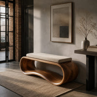 Wooden bench made from a looped ribbon frame with a slim cream cushion in an industrial loft entryway with exposed brick