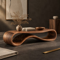 Corner detail of coffee table with a flat top over a looping wave shaped wooden base beside wood, brass and linen samples