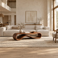Coffee table with a flat top over a looping wave shaped wooden base in a bright open plan living room