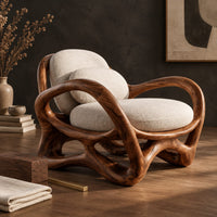 Corner detail of wooden chair with a looping ribbon frame and an interlaced base beside wood, brass and linen samples
