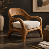 Corner detail of accent chair with looping arms, an open scooped back and a soft seat cushion beside wood, brass and linen samples