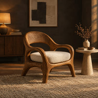 Accent chair with looping arms, an open scooped back and a soft seat cushion in a dark living room at golden hour