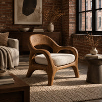 Accent chair with looping arms, an open scooped back and a soft seat cushion in an industrial loft living room with exposed brick