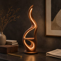 Corner detail of flame shaped floor lamp with glowing loops and a small flat ledge beside wood, brass and linen samples
