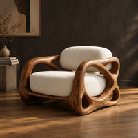 Armchair with looping carved wood arms and plush cream cushions, three-quarter view showing the grain