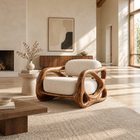 Armchair with looping carved wood arms and plush cream cushions in a bright open plan living room