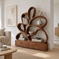 Bookshelf made of looping wooden ribbons set on a low two drawer base in a Scandinavian living room with white walls