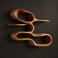 Wall shelf shaped as one looping ribbon of wood with open tiers, three-quarter view showing the grain
