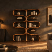 Bookshelf of looping tiers joined by a central trunk and thin shelves in a dark living room at golden hour