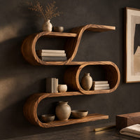 Corner detail of looping wooden wall shelves with a middle oval cell and curled ends beside wood, brass and linen samples