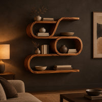 Looping wooden wall shelves with a middle oval cell and curled ends in a dark living room at golden hour