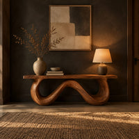 Bench with a flat slab seat on a looping wave shaped base in a dark entryway at golden hour