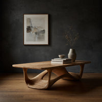 Looping wave base coffee table with pale top in a dark studio against a charcoal wall