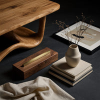 Corner detail of looping wave base coffee table with pale top beside wood, brass and linen samples