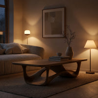 Looping wave base coffee table with pale top in an evening room lit by two lamps