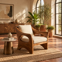 Lounge chair with oval side cutouts and an arched wooden base in a bright living room with arched windows and plants
