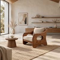 Lounge chair with oval side cutouts and tan cushions in a bright open plan living room