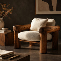 Corner detail of lounge chair with thick log style arms, post legs and cream cushions beside wood, brass and linen samples