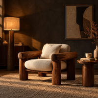 Lounge chair with thick log style arms, post legs and cream cushions in a dark living room at golden hour