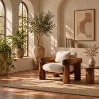 Lounge chair with thick log style arms, post legs and cream cushions in a bright living room with arched windows and plants