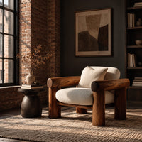 Lounge chair with thick log style arms, post legs and cream cushions in an industrial loft living room with exposed brick