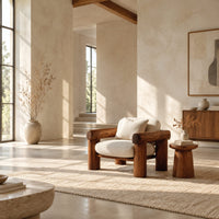 Lounge chair with thick log style arms, post legs and cream cushions in a bright open plan living room