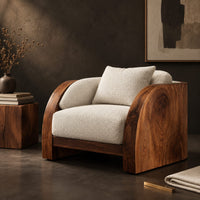 Corner detail of lounge chair with wide solid wood arm panels and a cushioned seat beside wood, brass and linen samples