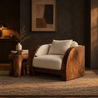 Lounge chair with wide solid wood arm panels and a cushioned seat in a dark living room at golden hour