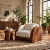 Lounge chair with wide solid wood arm panels and a cushioned seat in a bright living room with arched windows and plants