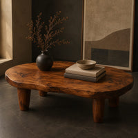 Corner detail of low bean shaped coffee table with a rich grained top and four tapered legs beside wood, brass and linen samples